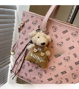 Gros plan d'un bijou de sac ours en peluche avec salopette marron sur un sac rose
