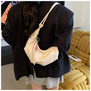 Détail du sac croissant blanc cassé avec bandoulière nouée et pompon coloré