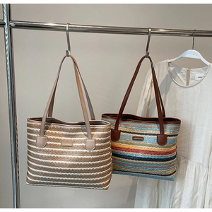 Détail de sacs cabas en paille rayés avec lanières en cuir dans un dressing