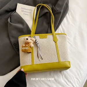 Detail view of canvas tote bag with lime green leather trim and cute bear charm