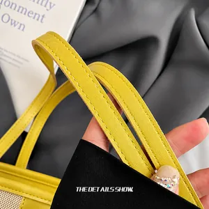 Detail of yellow leather tote bag showing double handles with reinforced stitching and oil edge
