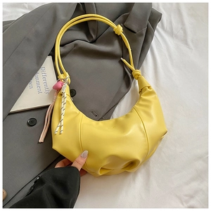 Detail of yellow crescent moon bag with stylish knot strap and pink heart charm