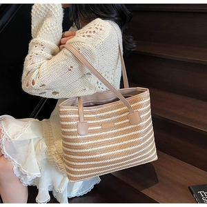 Détail du sac cabas en paille rayé avec bandoulière en cuir porté par un mannequin