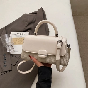 Detailed view of cream crossbody bag featuring woven texture and silver metal clasp detail
