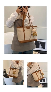 Detail of canvas tote bag with brown leather trim and cute teddy bear charm accessory
