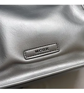 Makroaufnahme der silbernen Lederfalten und des Metall-Logos auf der Mini-Tasche