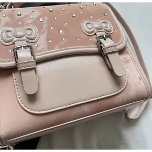 Close-up of pink bag with rhinestone flap, dual bow accents and silver buckles