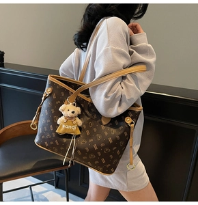 Détail du cabas monogramme marron foncé avec charm d'ours blanc et poignées jaunes élégantes