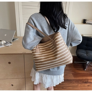 Détail du sac cabas rayé en paille avec lanières en cuir brun et texture tressée naturelle