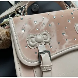 Close-up of pink bag featuring a bow, silver rhinestones and plush pom-pom charm
