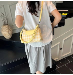 Détail du sac à carreaux jaune avec poignée tissée et bandoulière réglable