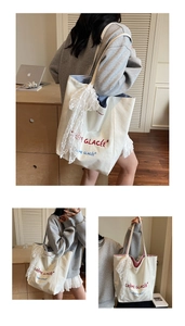 Detail of canvas tote bag featuring delicate white lace trim and blue striped inner lining