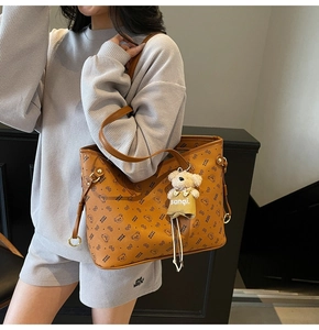 Détail d'un sac cabas imprimé marron avec un pendentif ours et une grande capacité