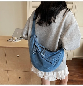 Detailed macro shot of blue denim crescent bag with fringe zipper and wide strap