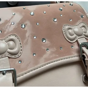 Detail of pink beige handbag with rhinestone decor and signature bow stitching