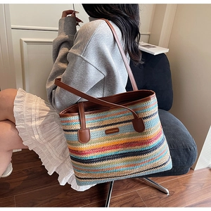 Détail du sac cabas en paille arc-en-ciel avec anses en cuir et logo mode métallique