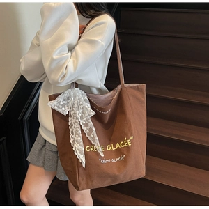 Brown canvas tote bag featuring a large white lace bow and Creme Glacee text print