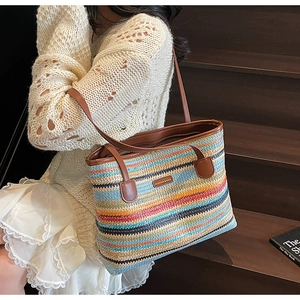 Détail du sac cabas tissé en paille arc-en-ciel avec anses en cuir marron et logo