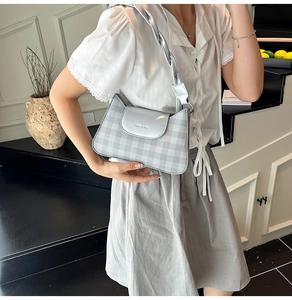 Gros plan d'un sac bandoulière argenté à carreaux avec bandoulière tressée et texture tissu