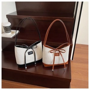 Detail of canvas tote bags with leather trim and decorative bow knots on wooden stairs