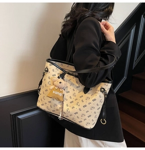 Détail du sac cabas imprimé avec breloque ours, porté par un mannequin stylé
