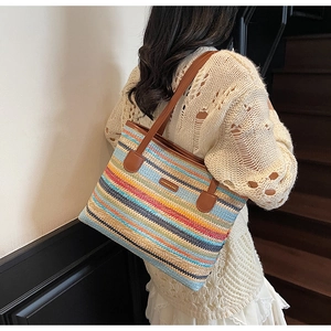 Détail d'un sac cabas en paille tissée colorée avec bandoulière en cuir et logo métallique