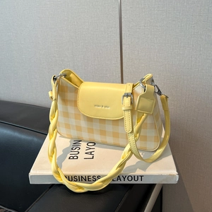 Détail du sac bandoulière à damier jaune avec logo et poignée tissée design