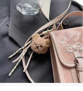 Detail view of pink patent leather handbag featuring a plush bear charm and bow decoration