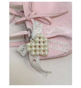 Détail d'un charme de sac en perles en forme de cœur avec dentelle sur sac rose