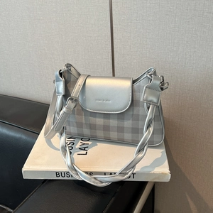 Détail du sac argenté métallisé avec motif à carreaux et logo embossé sur support