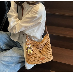 Close-up of beige crochet tote bag texture with leather strap and cute doll pendant