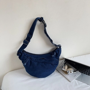 Detail view of crescent navy denim crossbody bag with adjustable black nylon shoulder strap