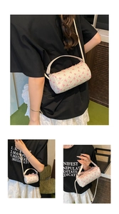 Close-up of cylindrical white crossbody bag with pink bow patterns and pleated texture