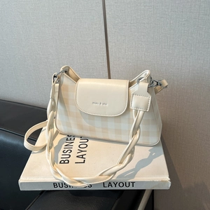 Détail du sac à bandoulière crème avec poignée tressée et logo de la marque