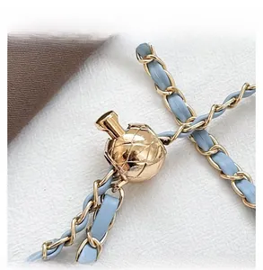Detail of light blue leather woven chain strap with adjustable gold quilted metal ball
