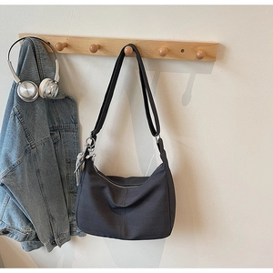 Detailaufnahme der dunkelgrauen Canvas-Hobo-Tasche am Haken mit Lifestyle-Accessoires