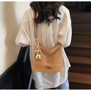 Detail of hand-woven crochet tote bag in caramel brown with doll and pearl charms