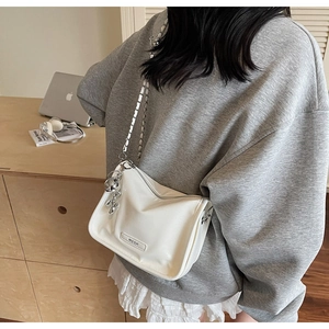 Detail der weißen Mini-Tasche aus Leder mit silberner Kette und MCOK-Metalllogo