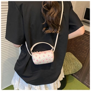 Detail of a creamy white cylindrical mini bag featuring sweet pink bow patterns and handle