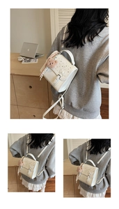 Close-up of white mini backpack featuring embossed bow, rhinestones, and bear charm