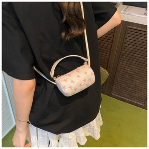 Rear view of a model wearing the mini cream crossbody bag with pink bow patterns
