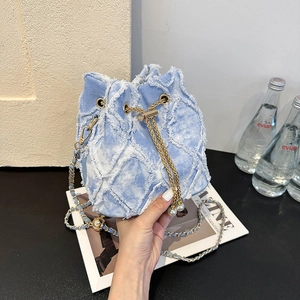 Detail of light blue denim bucket bag featuring frayed lattice texture and pearl drawstring