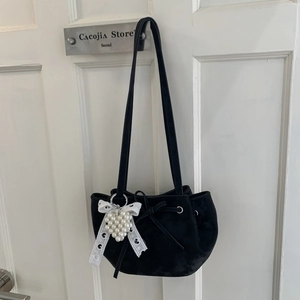 Détail du sac hobo noir mat avec pendentif cœur en perle et nœud en dentelle blanche