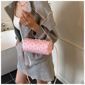 Pink bow patterned cylinder bag with ruffle trim shown as a stylish crossbody on model