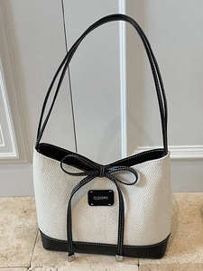 Large straw woven beach tote bag for women with black leather trim and bow detail