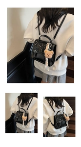 Detail of black glossy backpack featuring white pearl studs and plush bear charm