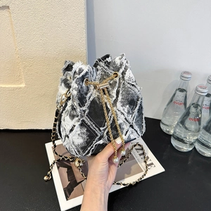 Detail of a denim bucket bag with frayed edges and pearl chain shoulder strap decoration