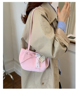 Vue latérale d'un sac à bandoulière rose en daim avec nœud en dentelle et perles sur modèle