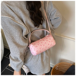 Detail of pink cylindrical shoulder bag with bow print and ruffled quilted texture