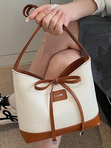 Minimalist beige woven straw tote bag with brown leather trim and bow details